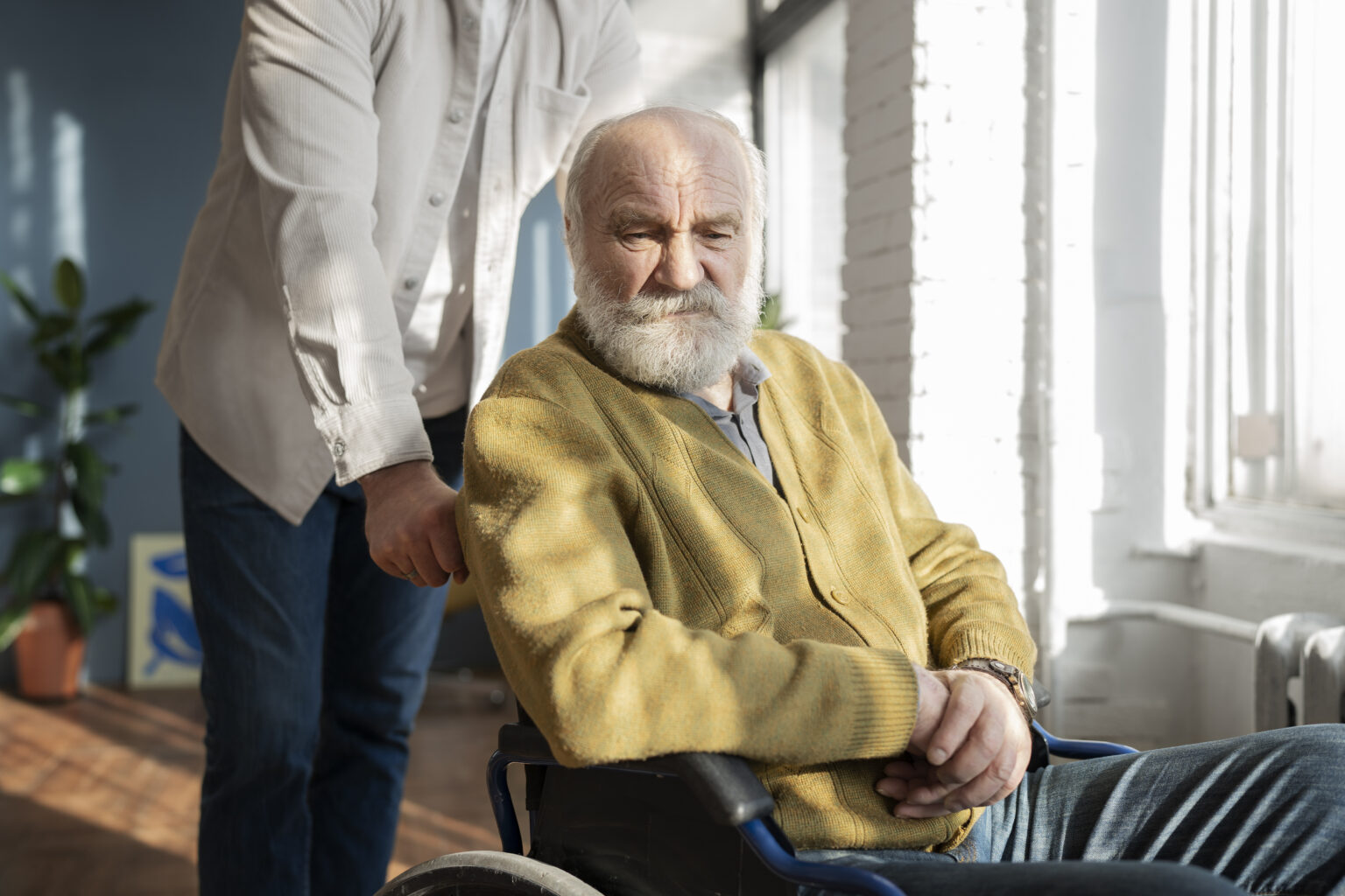 Elderly man in wheelchair with caregiver